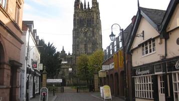 A street view with a historic church tower in the background, a cafe, and a building with a sign that reads "Chequers".