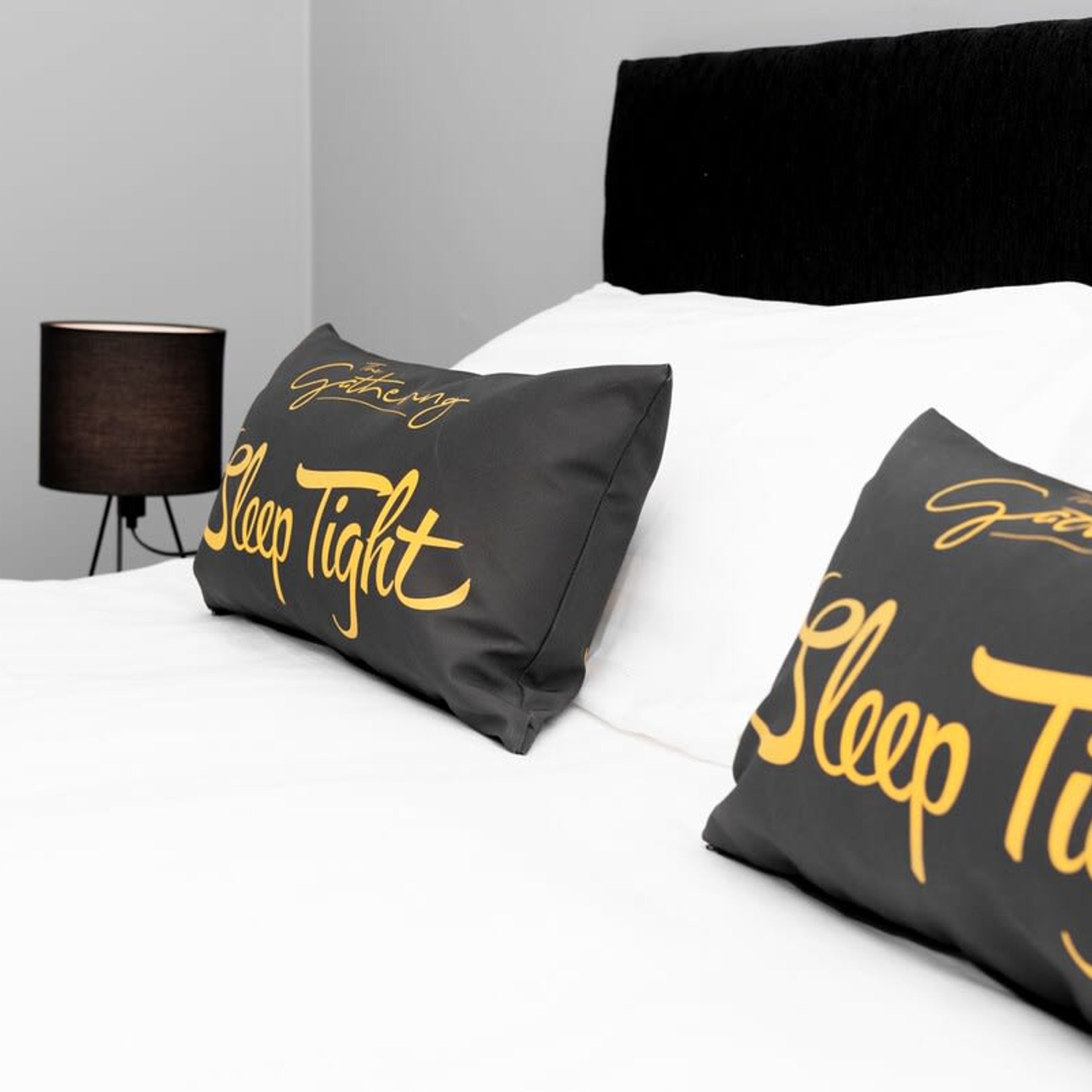 A bed with two pillows that read "Sleep Tight" in gold lettering.