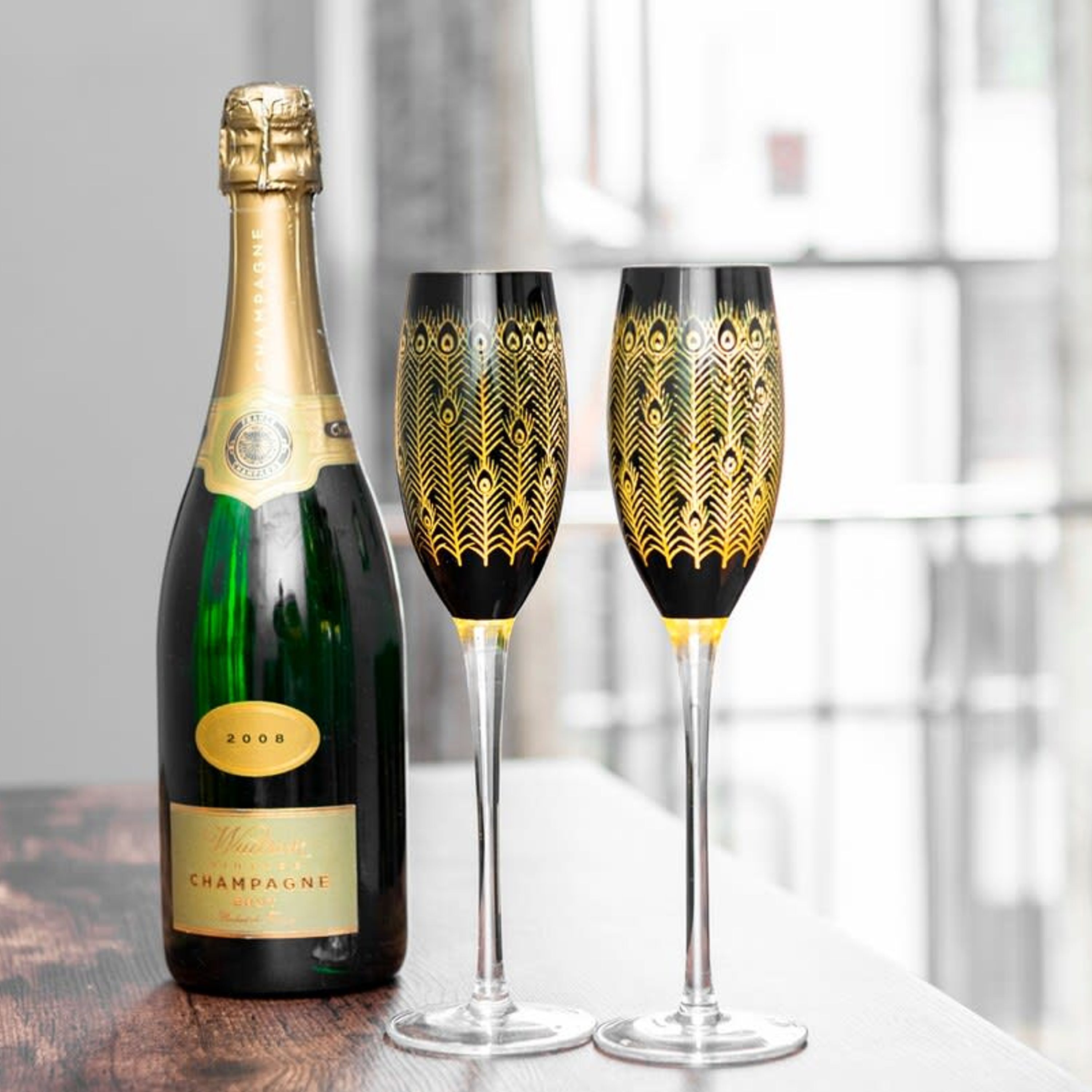 A bottle of champagne and two glasses with intricate designs.
