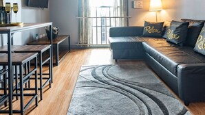 Un salon moderne avec un canapé, une table basse, un téléviseur et une fenêtre avec des rideaux.