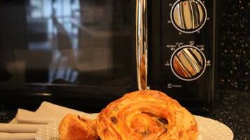 A microwave oven with a control panel, a plate with a pastry, and a napkin on a countertop.