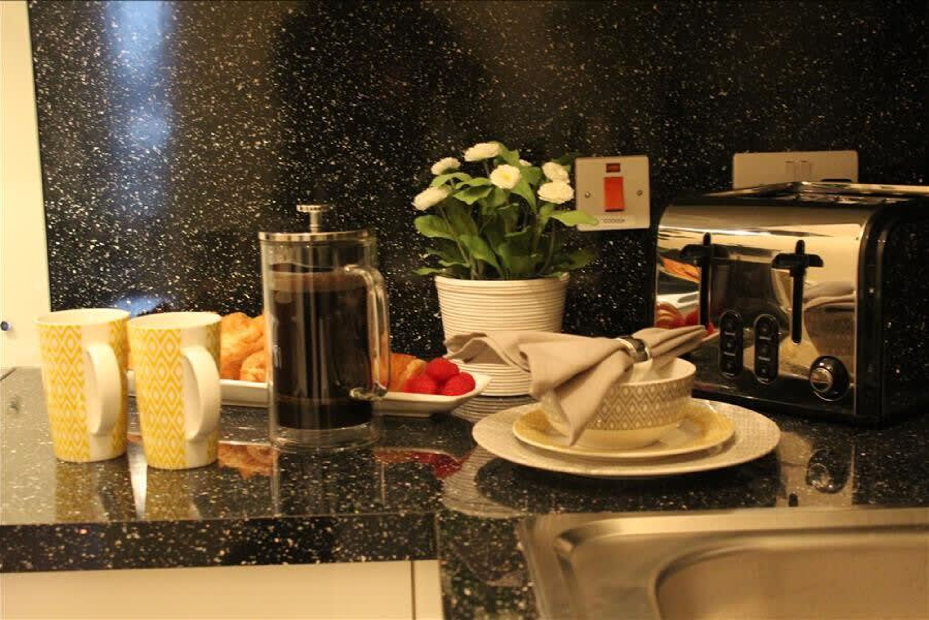 Eine Küchenarbeitsplatte mit Kaffeemaschine, Blumentopf, Toaster und einem Teller Essen.