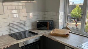 A modern kitchen with a stainless steel range hood, a microwave, and a wooden cutting board on the counter. - The Upper Gathering - Sleeps Up To 9 Sale (Sale)