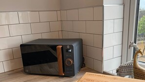 A kitchen with a microwave, a cutting board, and a window with a view of the outside. - The Upper Gathering - Sleeps Up To 9 Sale (Sale)