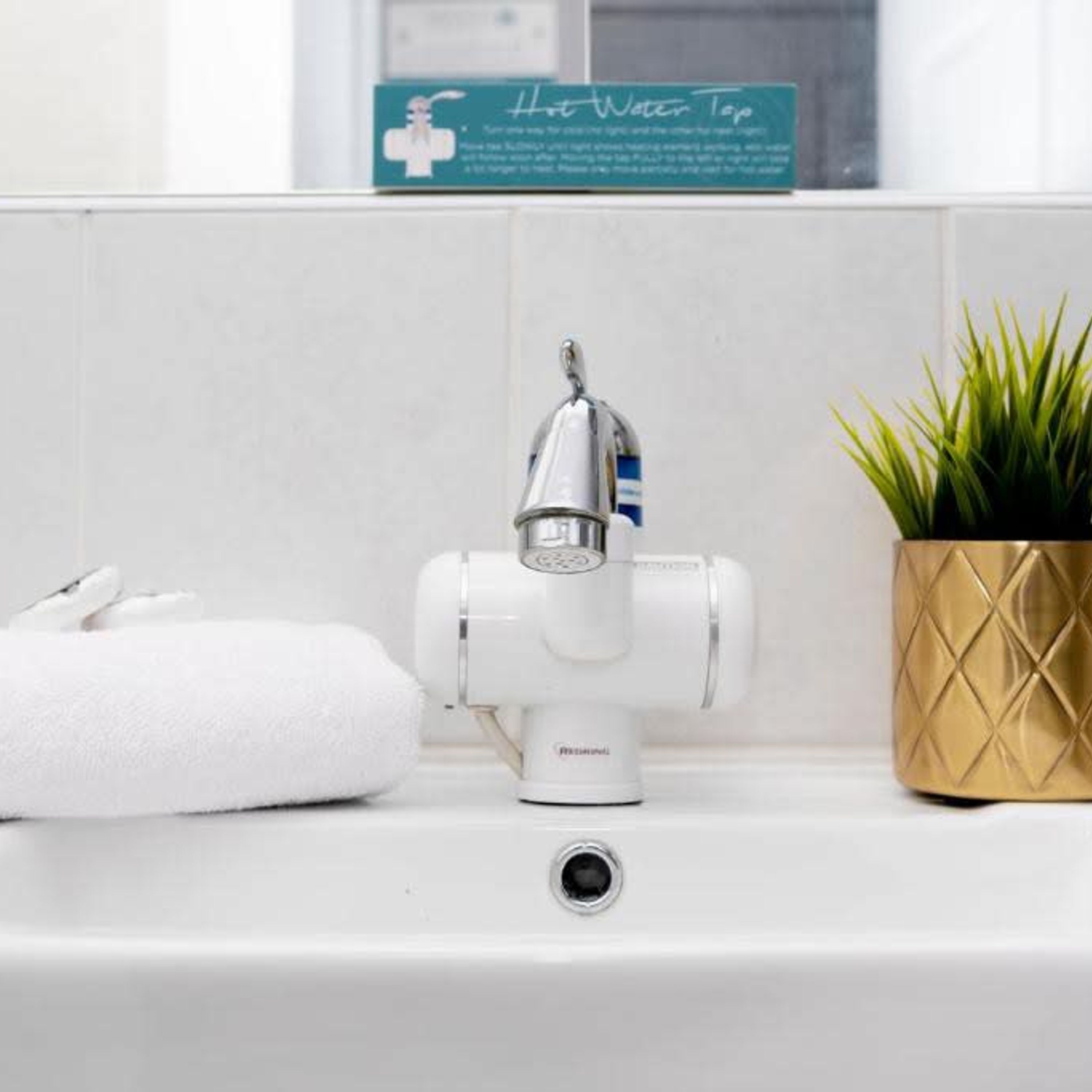 A bathroom sink with a faucet, a towel, and a potted plant.