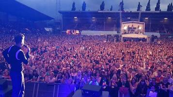 A large indoor venue with a stage at the front and a crowd of people.