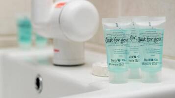 A bathroom sink with a faucet, a soap dispenser, and three tubes of shower gel labeled "Just for you".