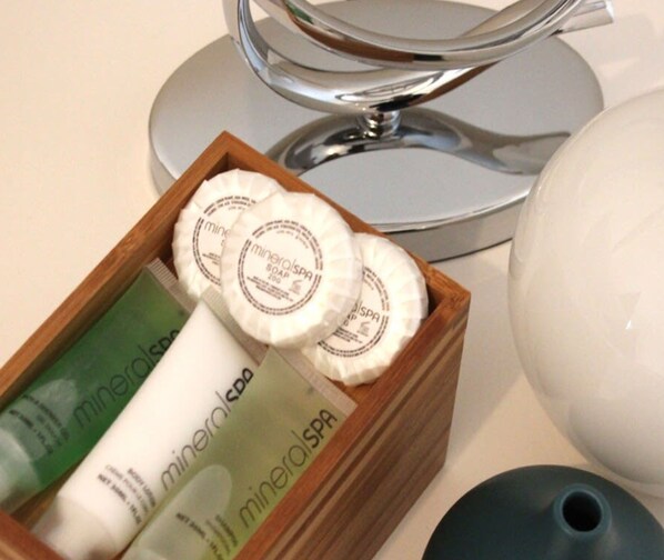 Una caja de madera con productos de spa mineral, incluyendo jabón y tubos de loción, y un jarrón de cerámica blanca.