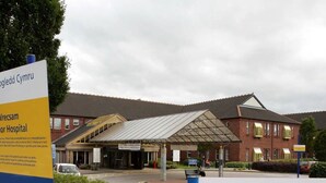A hospital entrance with a covered waiting area and a sign indicating directions to the emergency department.