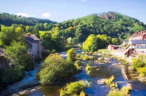 A river flowing through a town with historic buildings and lush greenery. - Wrexham Central Stay Apartment Six (Wrexham)