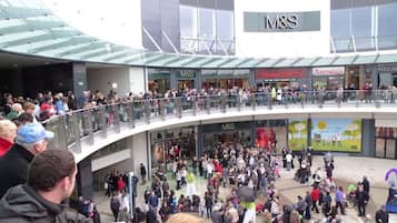 Un centro comercial concurrido con varias tiendas, entre ellas M&S, Frances & Benny y Nando's.