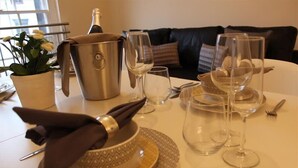 A dining table set with a bottle of champagne, wine glasses, and a bowl of fruit. - The Maelor - Berwyn House Central Wrexham (Wrexham)