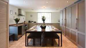 A modern kitchen with a dining table set for six, a built-in oven, and a large window providing natural light.