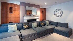 A modern living room with a sectional sofa, a fireplace, and a wall clock.