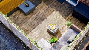 An outdoor patio with a wooden deck, seating areas, and a small table with a decorative item.
