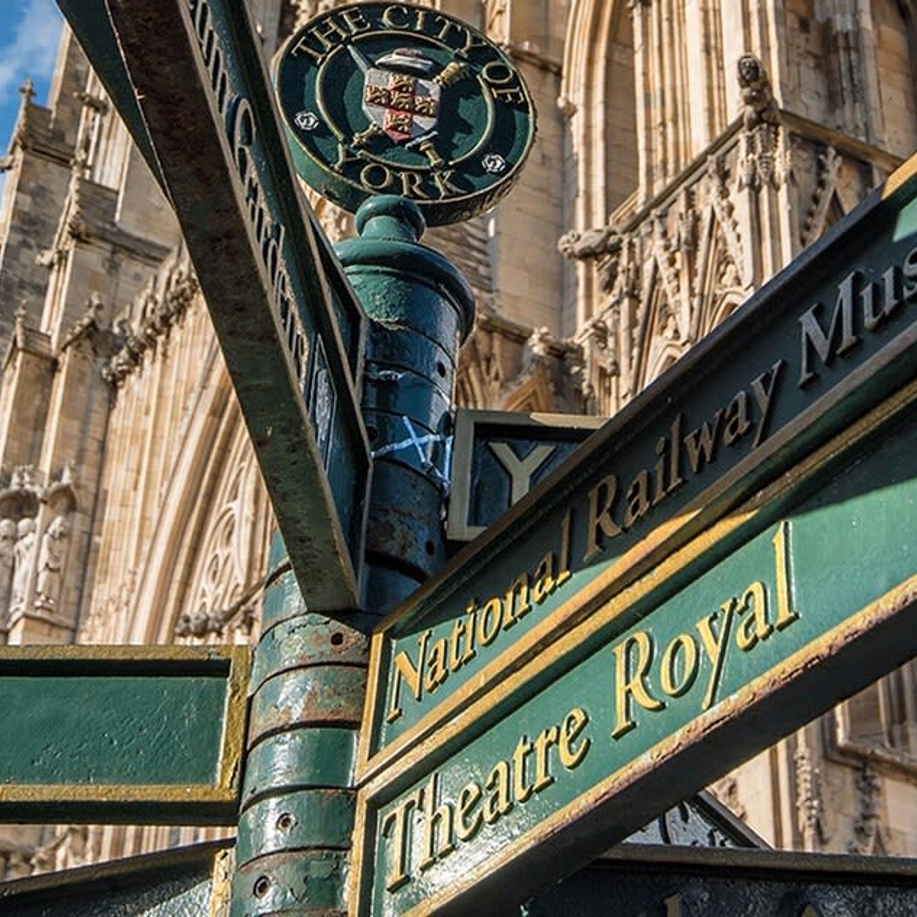 A signpost with "Theatre Royal" and "National Railway Museum" written on it, in front of a historic building.