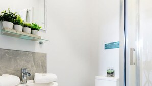 A modern bathroom with a glass shower enclosure, a white toilet, and a sink with a mirror above it. - Wrexham Central Stay Apartment Seven (Wrexham)