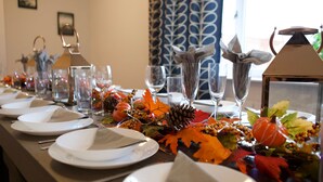 A table set for a meal with clear glassware, plates, and decorative elements like leaves and pinecones.