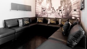 A modern living room with a sectional sofa, a radiator, and a cityscape mural on the wall.