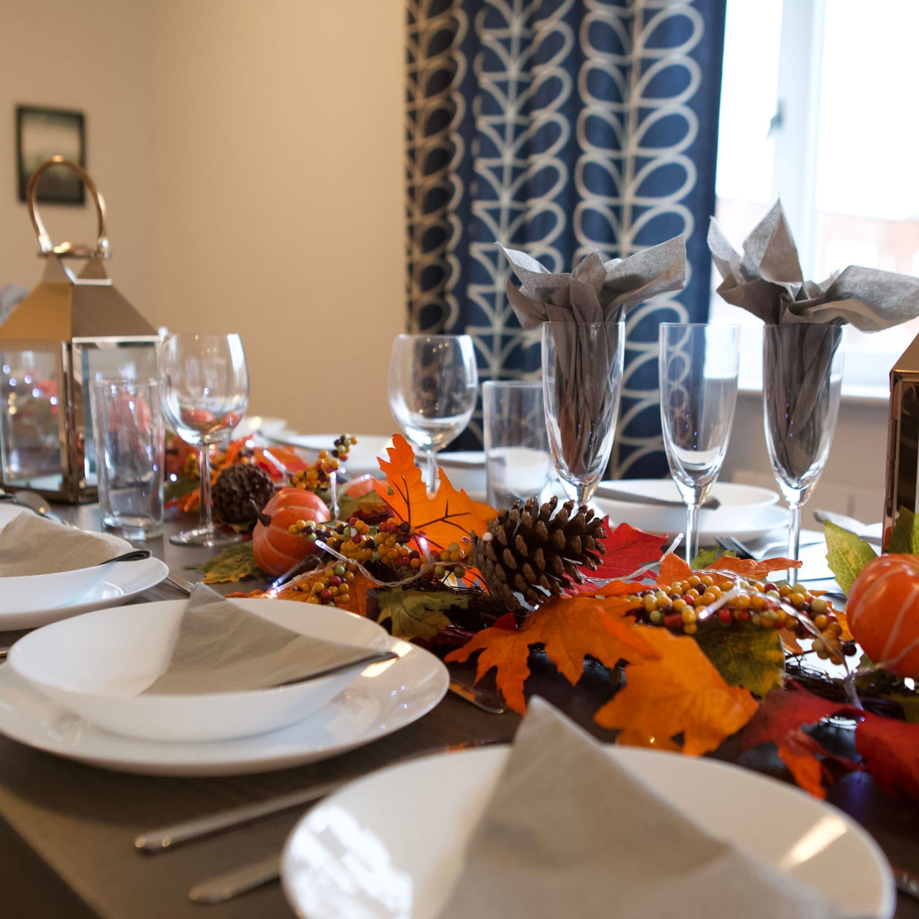 Une table à manger dressée avec de l’argenterie, des assiettes blanches et des verres transparents.