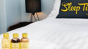 A neatly made bed with a pillow that reads "Sleep Tight" and three bottles of ELSYL on a white blanket.