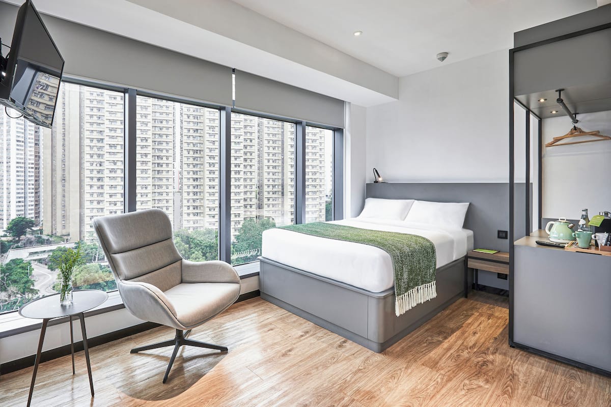 Une chambre moderne avec une grande fenêtre, un lit, une chaise et une petite table.