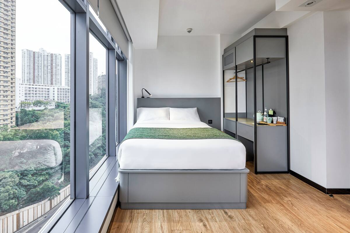 Une chambre moderne avec un grand lit, une armoire et une vue sur le paysage urbain.