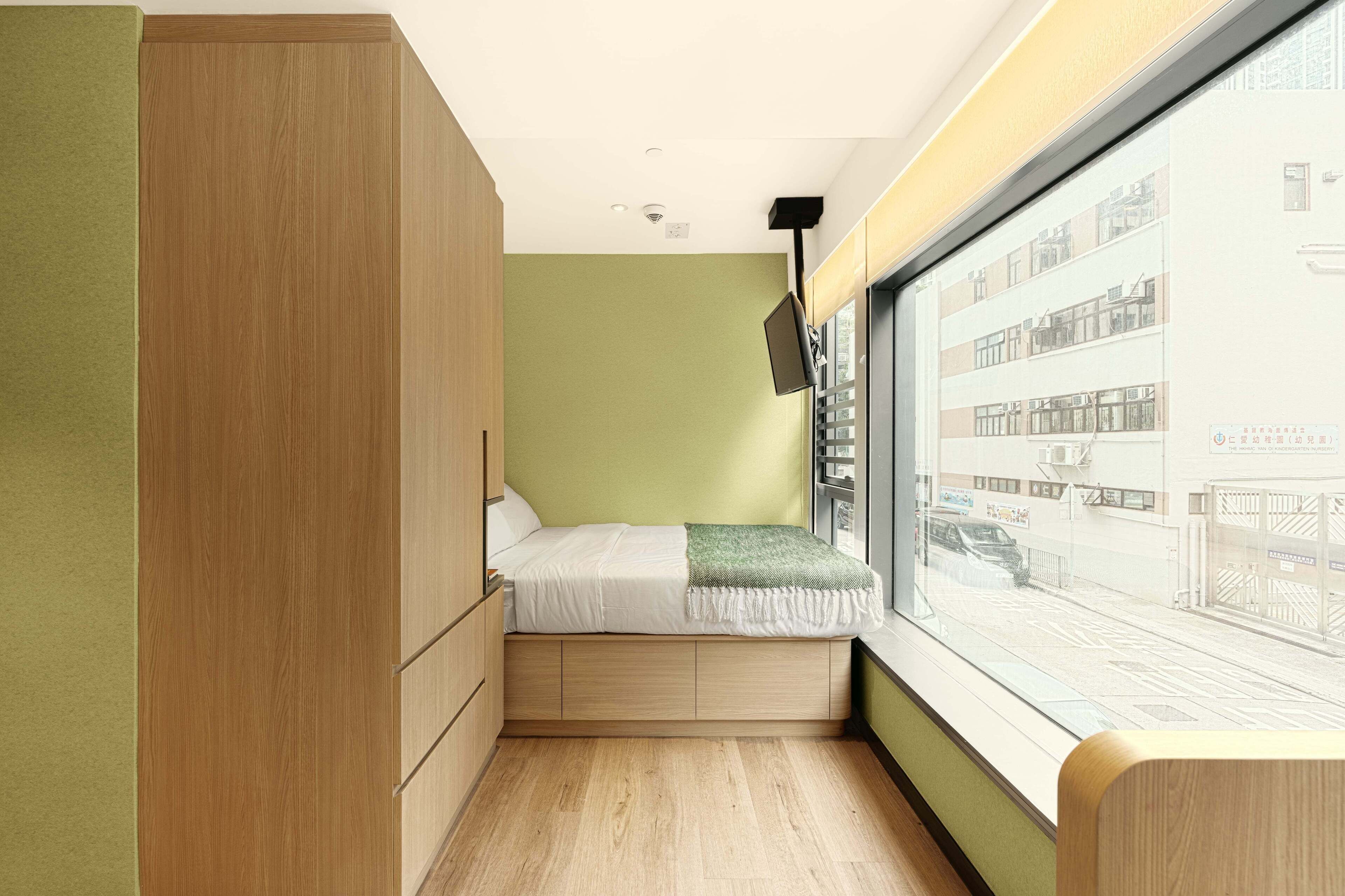 Un dormitorio pequeño con cama, ventana y vista a la calle.