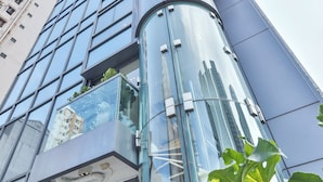 Een modern hoog gebouw met een glazen gevel en een gebogen entree.