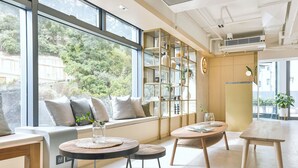 Een modern interieur met grote ramen, een ingebouwde boekenkast en een zithoek met een ronde tafel en een bank.