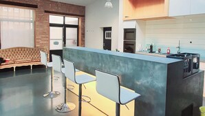 A modern kitchen with a central island, bar stools, and a skylight. - Loft für Besondere Momente (Mannheim)
