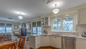 A spacious kitchen with white cabinetry, a dishwasher, and a large window.