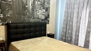 Ein Schlafzimmer mit einem großen Bett, einer Stadtansicht als Wandbild, einem Deckenventilator und gemusterten Vorhängen.