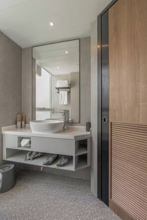 A modern bathroom with a large mirror, a vessel sink, and a towel rack. - Urbanwood Hung Hom (Kowloon)