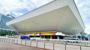 A modern building with a large overhanging roof, surrounded by a brick-paved area and metal barriers.