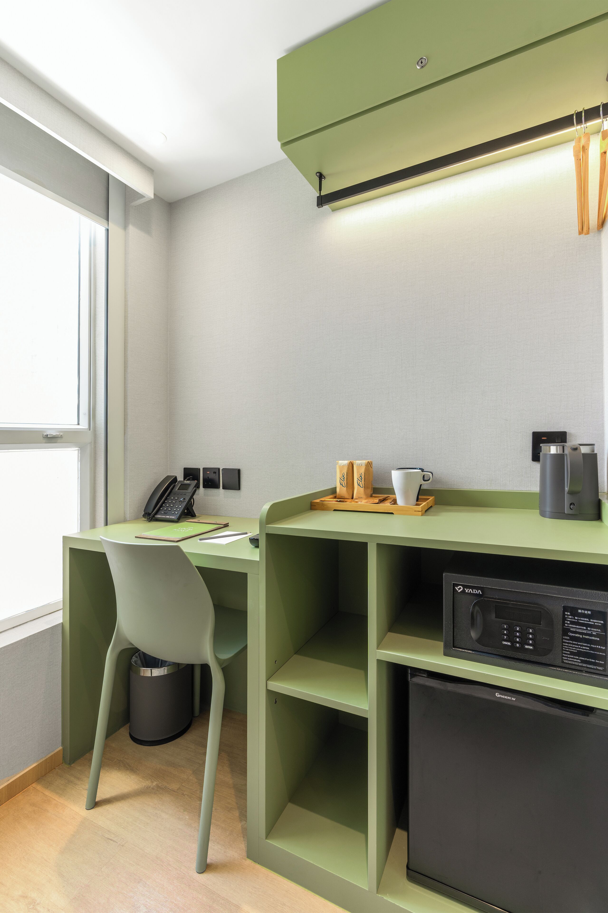 Un espacio de trabajo compacto con escritorio, silla, cafetera y refrigerador pequeño.