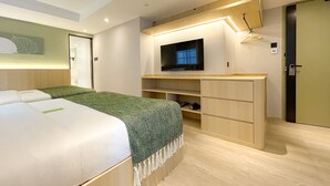 Een moderne hotelkamer met een bed, een aan de muur bevestigde televisie, een bureau met planken en een kledingkast.