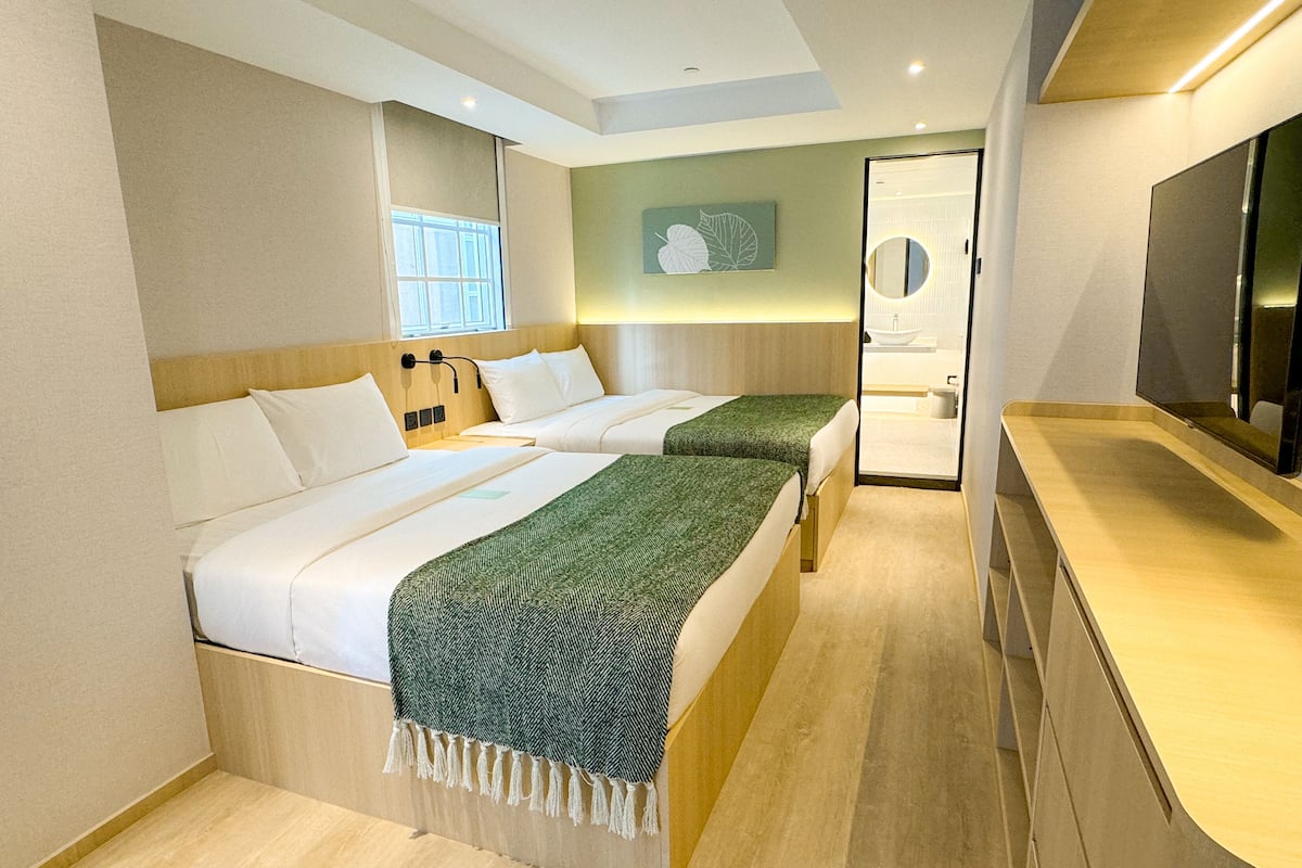 A hotel room with two beds, a bathroom, and a TV.