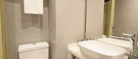 Un baño moderno con inodoro, lavabo y espejo.