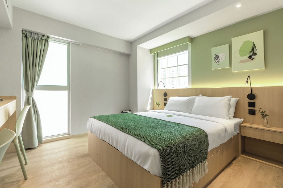 A modern bedroom with a large bed, a desk, and a chair.