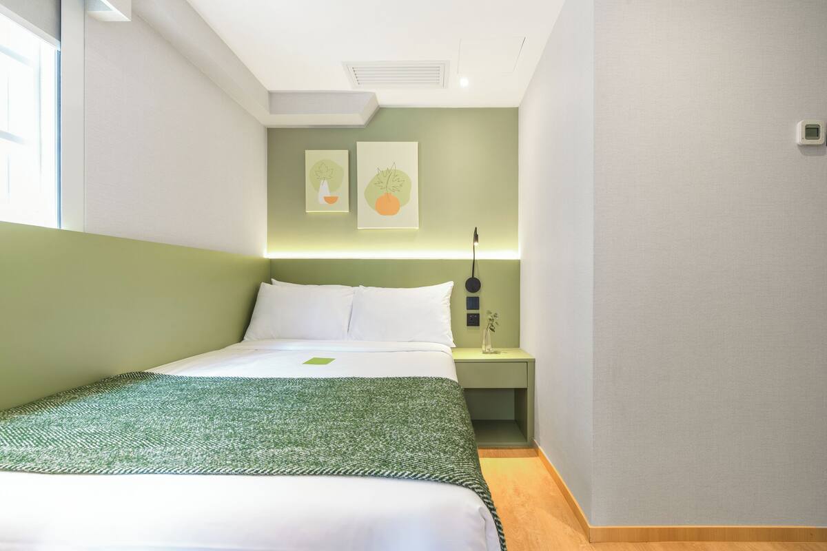 A neatly arranged bedroom with a bed, bedside tables, and artwork on the wall.