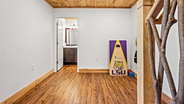 A hallway with wooden flooring and a wooden ceiling. A door leads to a kitchen area. - Cataloochee Chalet Mountain Views/Hot Tub/Fire Pit (Maggie Valley)