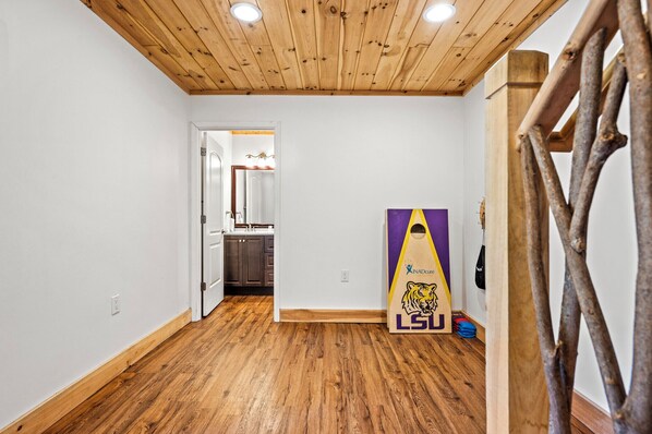 A hallway with wooden flooring and a wooden ceiling. A door leads to a kitchen area.