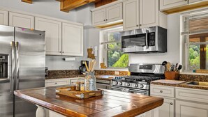 A modern kitchen with stainless steel appliances, a wooden island, and a view of greenery outside. - Cataloochee Chalet Mountain Views/Hot Tub/Fire Pit (Maggie Valley)