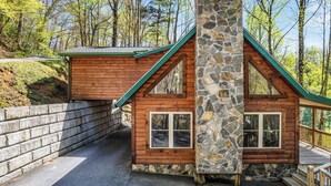 A cabin with a stone chimney, wooden walls, and a green roof. - Cataloochee Chalet Mountain Views/Hot Tub/Fire Pit (Maggie Valley)