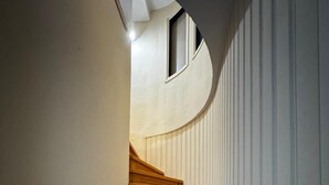 A wooden staircase with a curved wall and a small window at the top. - Moonbeam Townhouse Skiathos (Skiathos)