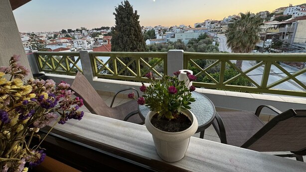 A balcony with a potted plant, a table, and chairs. - Moonbeam Townhouse Skiathos (Skiathos)