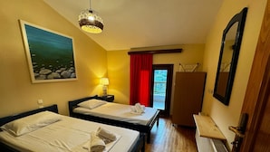 A hotel room with two beds, a painting, a lamp, a red curtain, and a view of the outside. - Moonbeam Townhouse Skiathos (Skiathos)