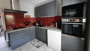 Eine moderne Küche mit grauen Schränken, einem Kühlschrank, einer Spülmaschine und einem Backofen von Bosch.