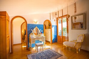 A room with a wooden floor, a blue and white wall, a vanity with a mirror, a white dresser, a gold-framed armchair, and a large mirror on the wall. - Majestic Villa in Hills of Florence with Gardens Gym Jacuzzi and Sauna (Fiesole)
